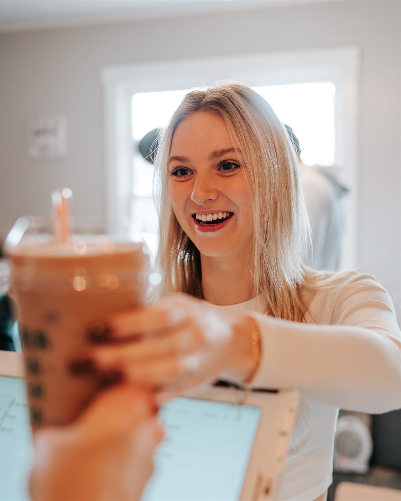 A teammate handing a chocolate protein shake across the counter