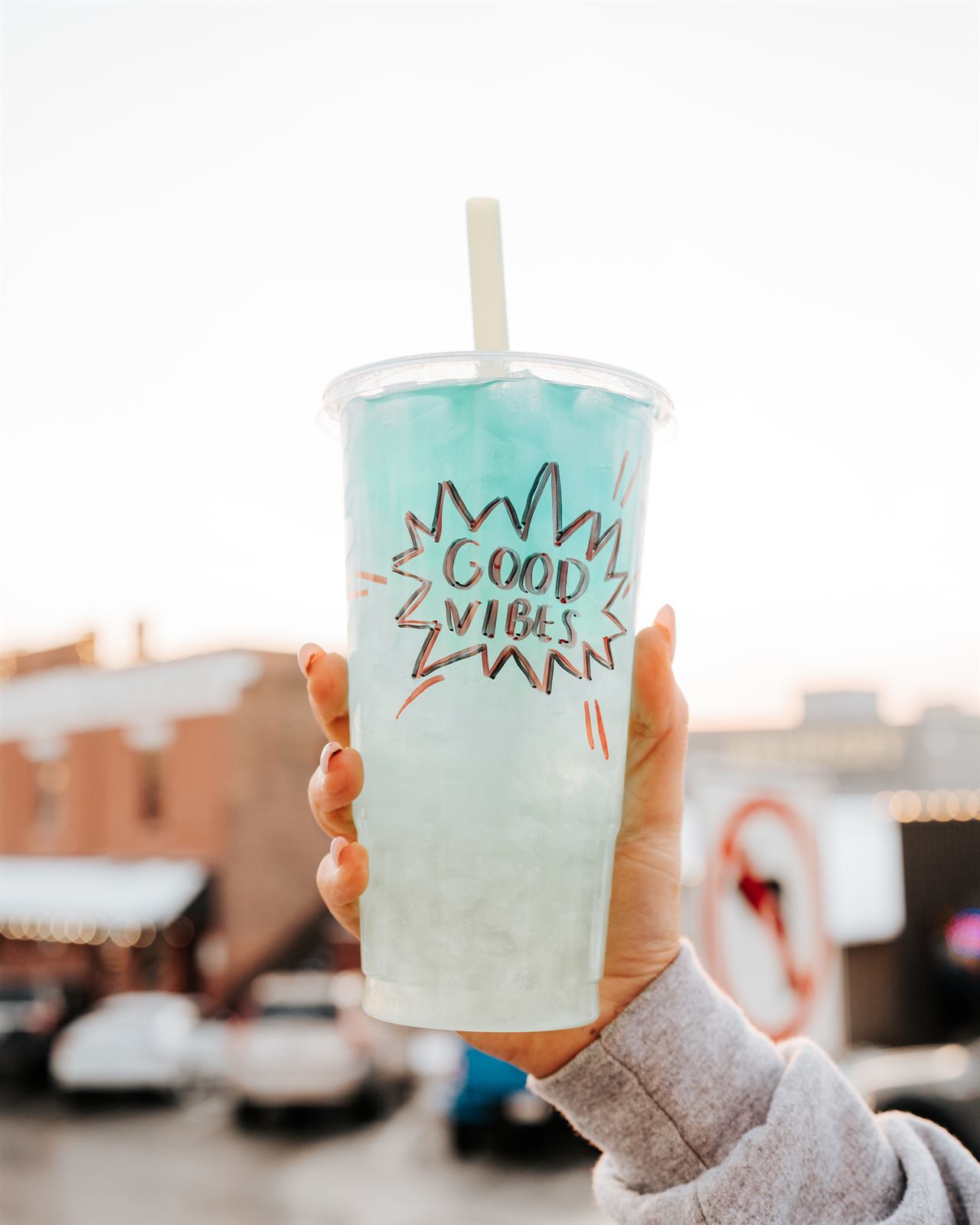 A teal Good Vibes tea held up on Corby Street