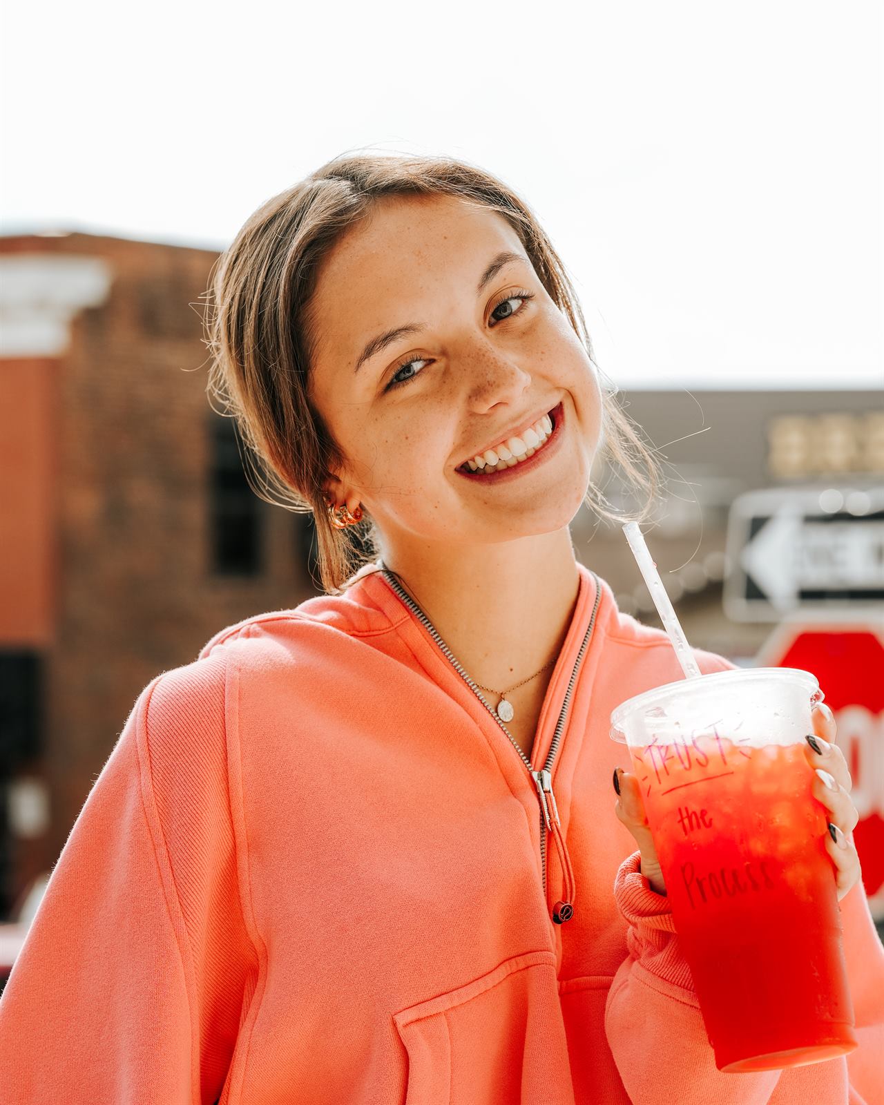 A smiling regular holding a red tea with Trust the Process written on the cup